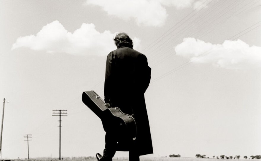 Johnny Cash with a long black coat and guitar case.