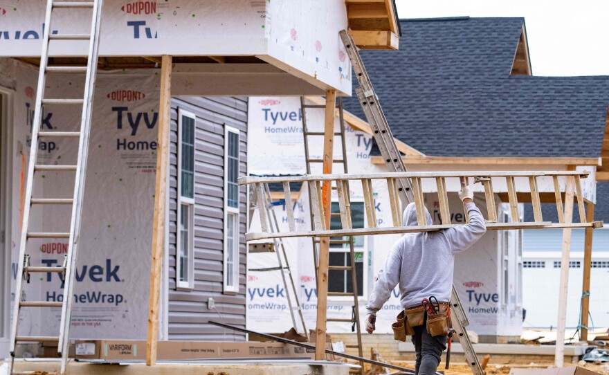 A man carries a ladder through new home construction in Trappe, Md., on Oct. 28, 2022. Mortgage rates have risen, hitting the housing sector.