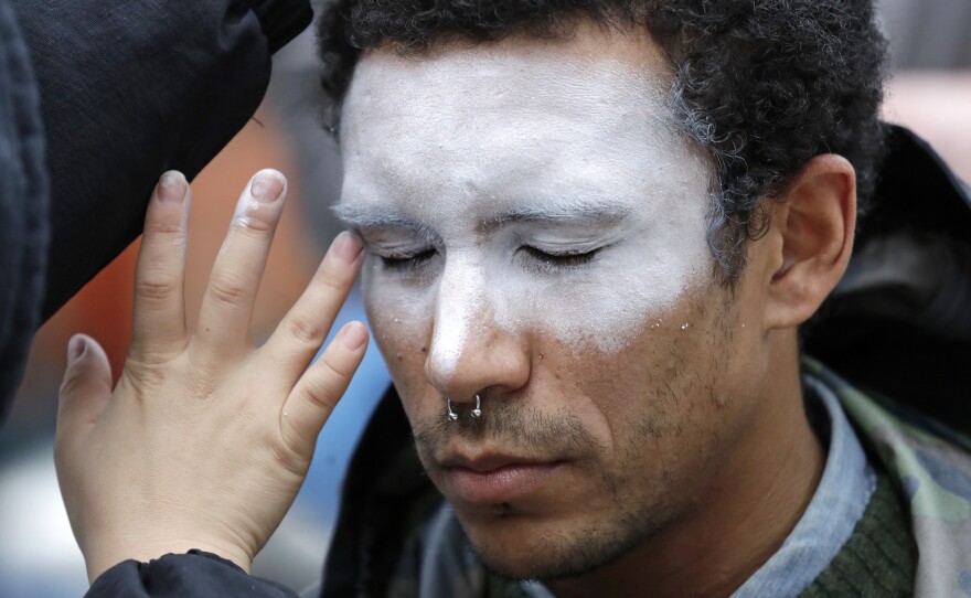 In this Oct. 31 photo, a man has his face painted to represent efforts to defeat facial recognition. It was during a protest at Amazon headquarters over the company's facial recognition system.