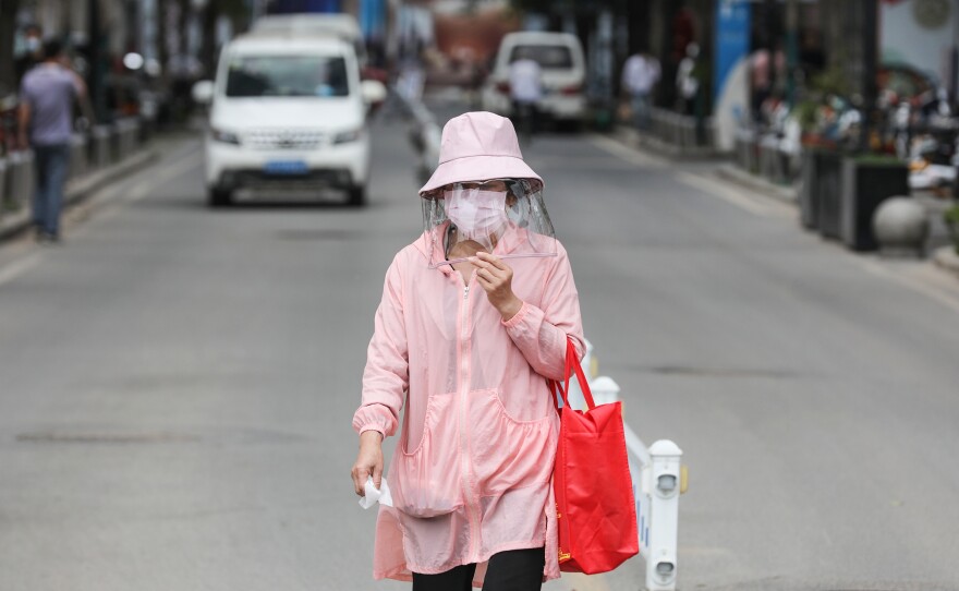 A woman wears a face mask on Monday as she walks along a street in Wuhan, in China's central Hubei province. Wuhan reported new cases of COVID-19 after going more than a month without new infections.