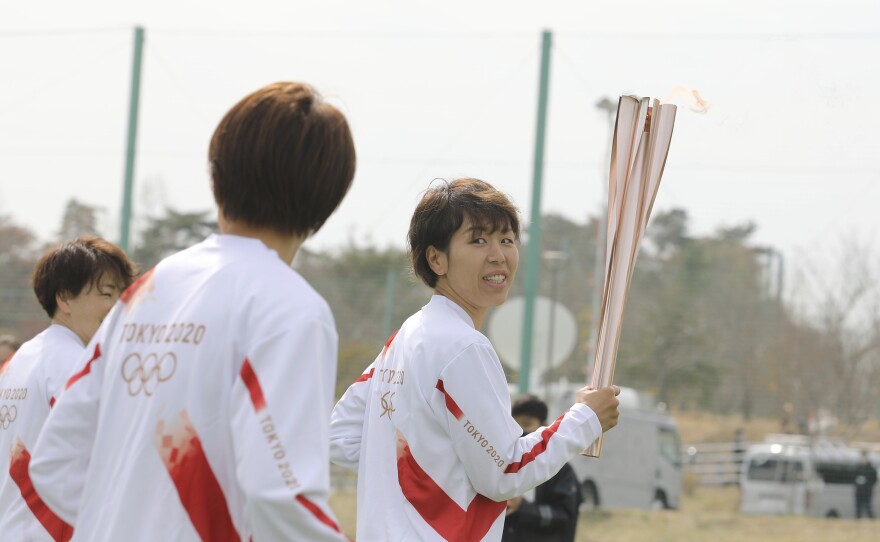 Azusa Iwashimizu (right) and other members of Japan women's national football team run as torchbearers in the first leg of the torch relay for Tokyo Olympics on Thursday in Fukushima prefecture, Japan.
