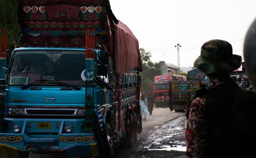 A brightly painted truck passes through Torkham while a Pakistani guard watches.