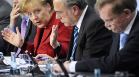 German Chancellor Angela Merkel (left) addresses a press conference Wednesday in an effort to calm investors about the looming European debt crisis. She said the emergency funds to Greece need to be accelerated.