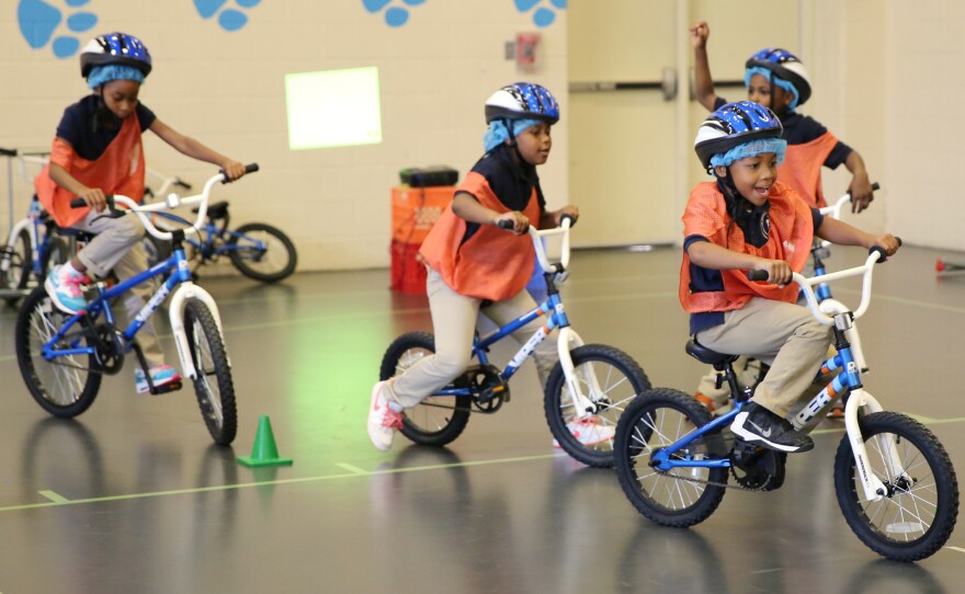 Second-graders ride in circles around the school's indoor gym.