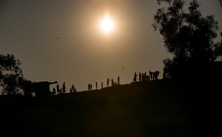 Children fly kites along a ridge in the camp. Many of the refugees fled Myanmar with only a few possessions. For some kids homemade kites are the only toys they have.