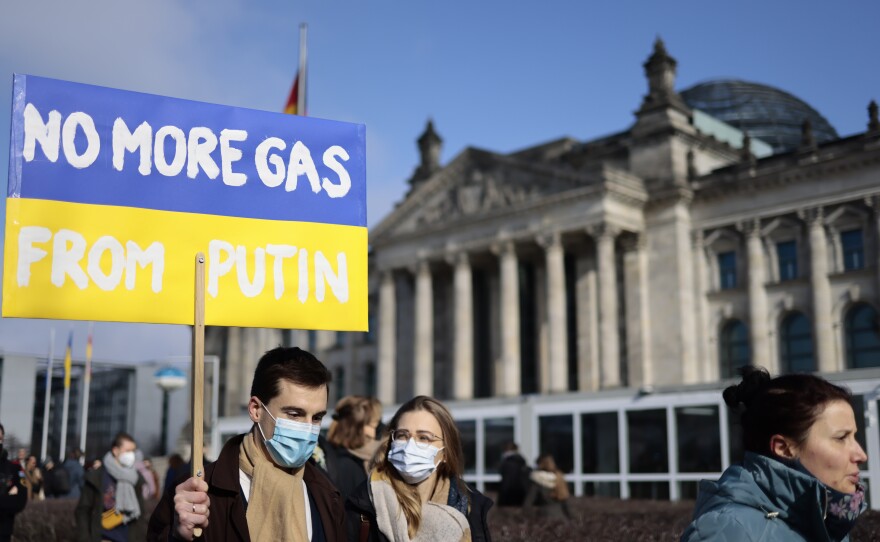 A man with a sign saying "No More Gas From Putin" passes the Reichstag building where the German Chancellor Olaf Scholz delivered a speech on the Russian invasion of the Ukraine during a meeting of the German federal parliament in Berlin on Feb. 27.