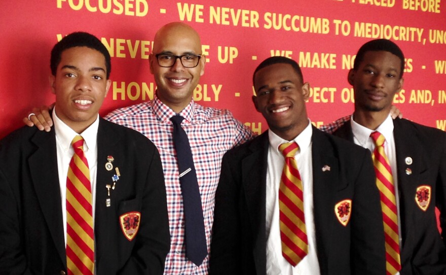 Urban Prep founder Tim King stands in front of the school's "We Believe" creed with three of the school's graduates. Steven Clark (left), 17, will attend Denison University, Dwayne Mitchell, 18, will go to the University of Illinois and Derrick Little (right), 17, will attend Georgetown University.