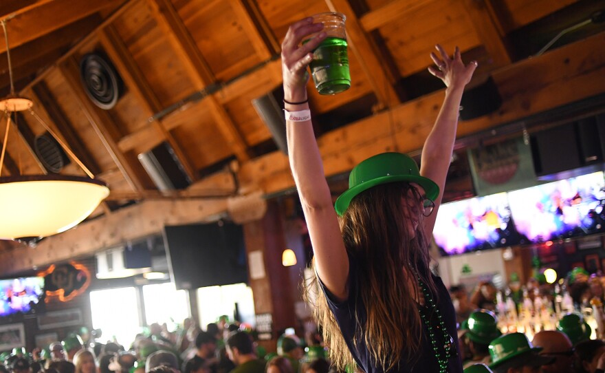 A woman dances while sitting on her friend's shoulders during St. Patrick's Day festivities in Denver last year.