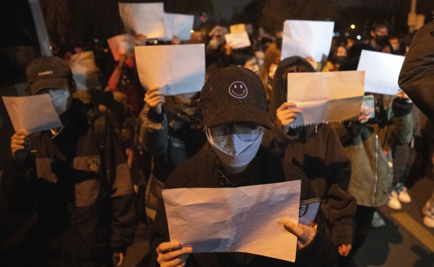 Protesters hold up blank sheets of paper and chant slogans as they march to protest strict anti-virus measures in Beijing on Nov. 27, 2022. Thousands of people demonstrated across China, waving sheets of white paper to represent the country's strict censorship.