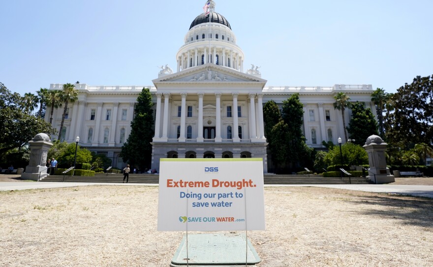 A sign about saving water is posted on browning grass outside the state Capitol in Sacramento, Calif., on Monday, July 11, 2022. California's water use dropped more than 10% in July compared to two years ago, state officials said Wednesday Sept. 7, 2022. 