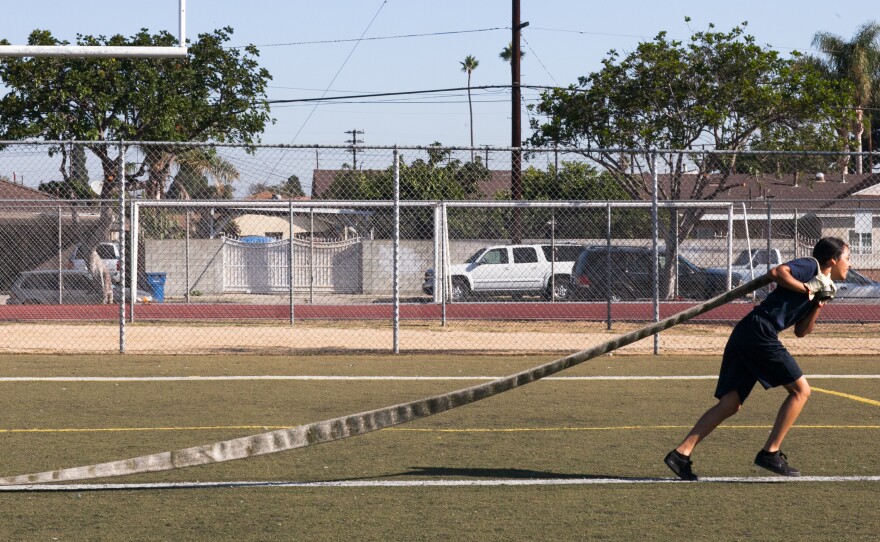 Students in the LAFD's new magnet school program race with fire hoses during a morning workout at Banning High.