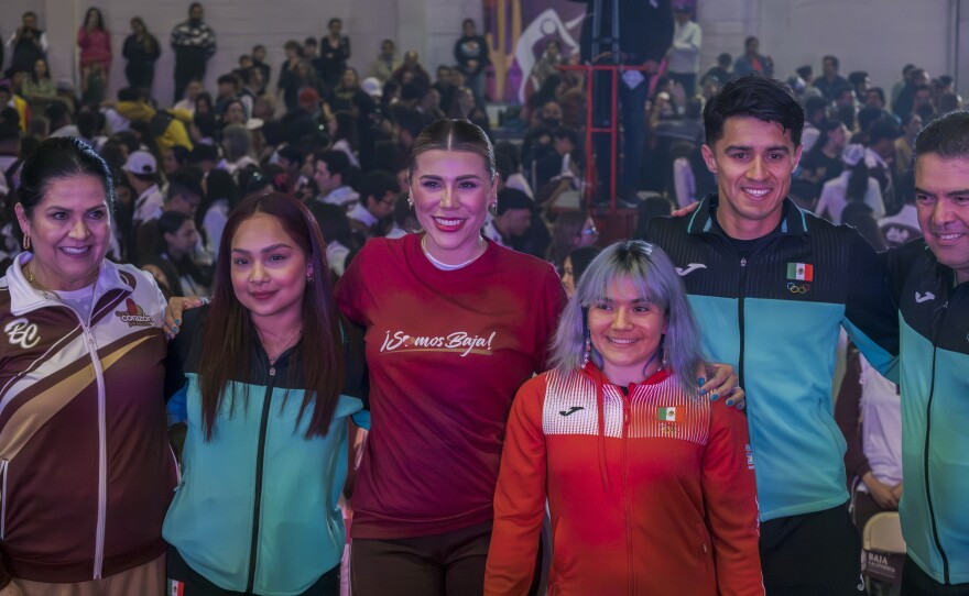 Three of Baja California's five Olympic athletes pose for photos with Governor Marina del Pilar Avila. from the right, rower Alexis Lopez, gymnast Alex Moreno, del Pilar Avila, and gymnast Natalia Escalera.