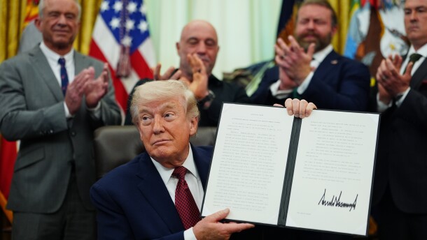 President Donald Trump holds up a signed executive order in the Oval Office of the White House on Saturday in Washington.