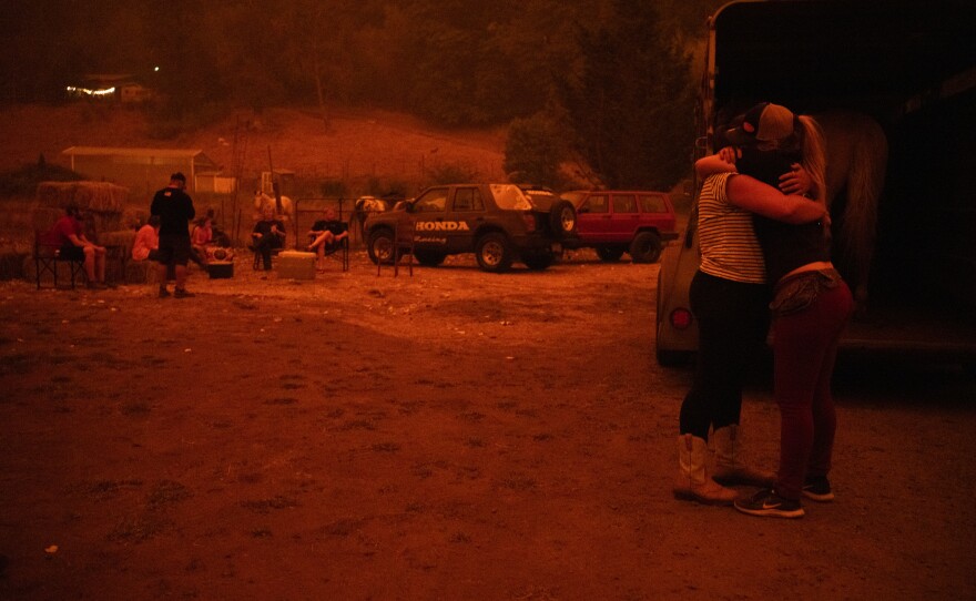 Chance Johnson hugs Sarah Hunter. The two loaded a horse into a trailer to be evacuated Wednesday in Canby, Ore.