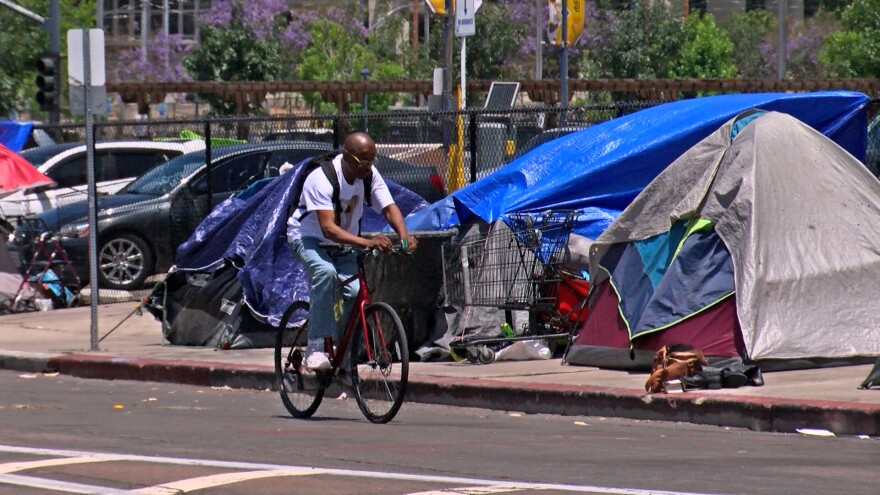 A man riding his bike through a homeless encampment in downtown San Diego, May 31, 2022.