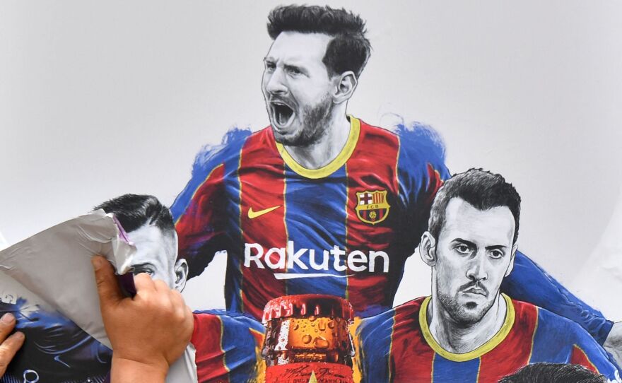 A worker removes posters featuring FC Barcelona's departing Argentinian star Lionel Messi on Tuesday. Messi is poised to join Paris Saint-Germain.