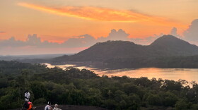 Sunset casts a warm glow over Colombia's remote Mavecure Mountains, where three towering rock formations rise above the Amazon jungle.