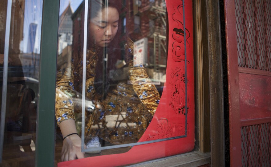 Artist Emily Mock installs a paper-cut display at Wing on Wo & Co.'s storefront window.