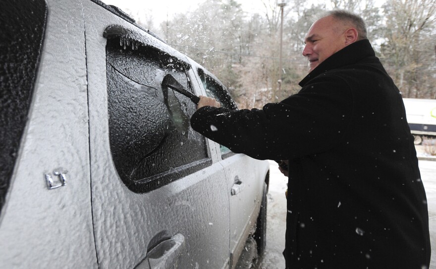 Dr. Rick Coslett scrapes a coating of ice of his vehicle in Kingston Township, Pa., on Friday.