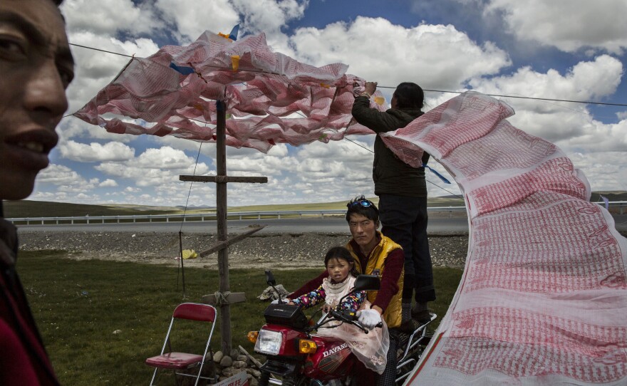 Tibetan nomads put up a string of Buddhist prayer flags in Qinghai, China. They face many challenges to their traditional way of life, including political pressure to resettle, climate change and rapid modernization.