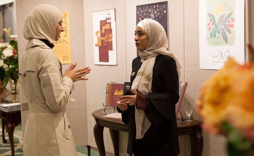 Rawabi al-Sanusi, 23, (right) speaks with another artist at the exhibition at the Saudi embassy. "I always liked to draw," she says. "I was like the weird one in my family." She designed a hardcover book paying tribute to generations past, "to show the diversity of Saudi Arabian families," she says. Her great-great-grandfather, she says, "was a king of Libya for a short time."