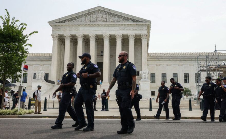 U.S. Capitol police officers walk near the Capitol complex on July 19. Congress is voting to extend funding for the force.