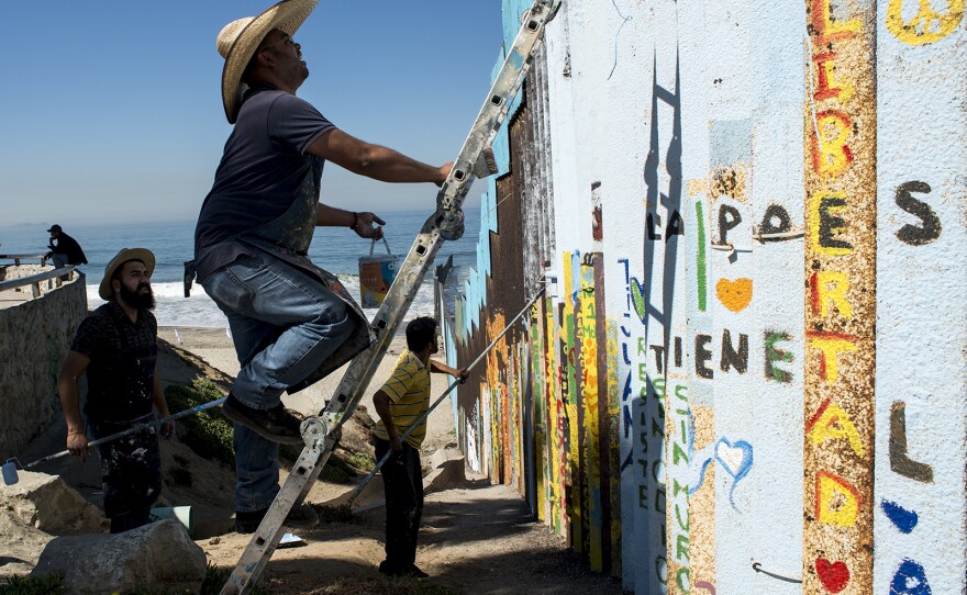 From left, Luis Marmolejo, Enrique Chiu and Sergio Tellez, begin painting sections of fencing along the U.S.-Mexico border at Friendship Park in Tijuana on Oct. 7, 2017. Chiu, a muralist, has worked for nearly a year to paint messages of hope in what could become the world’s largest mural.