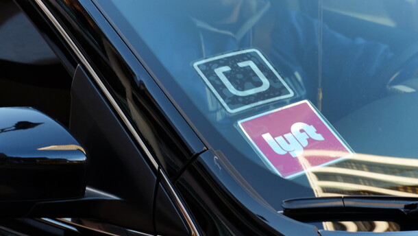 A driver displays Lyft and Uber stickers on his front windshield as he drops off a passenger in downtown Los Angeles, Jan. 12, 2016.