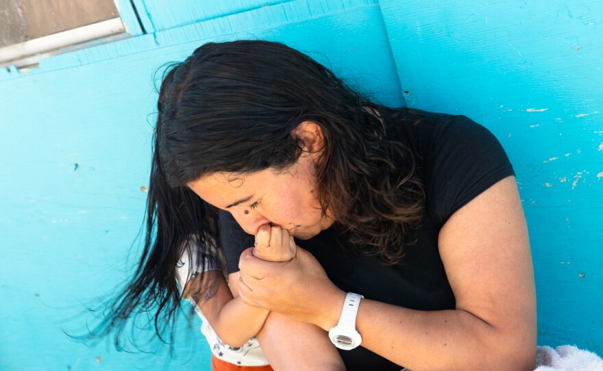 A mother from the state of Mexico kisses the hand of her daughter at a shelter in Tijuana, Oct. 22, 2023. She fled her home with her two daughters and is seeking asylum in the United States.