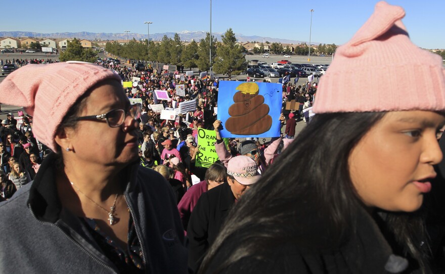 Protesters carry signs as they make their way to Sam Boyd Stadium on Sunday.