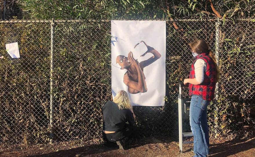 Students Kate Zimmerman and Victoria Severance install Sheena Rae Dowling's "The answers aren't down there. I already looked.," part of the Mesa College Art Gallery drive-thru exhibition opening Nov. 13, 2020. At left is a placeholder where extra tree trimming is needed before installing the next piece.