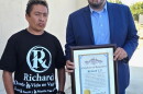 Carlitos Ricardo Parias (left) receives a certificate of recognition from Jose Ugarte, chief of staff for Los Angeles City Council member Curren Price, in Los Angeles in August 2025.