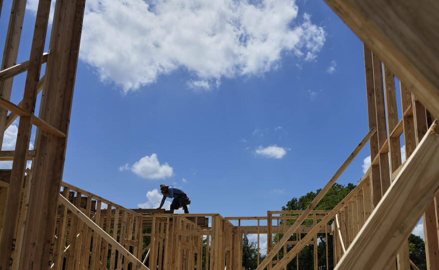 Workers work on the roofing structure of new home under construction, Tuesday, July 15, 2025, in Richardson, Texas.