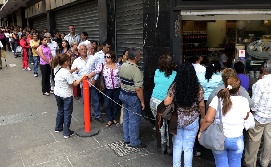 Venezuelans line up to buy goods at a store in Caracas on March 10. Protesters have been taking to the streets for weeks over the country's troubled economy and other issues. The government introduced a new foreign currency exchange system on Monday, seeking to stabilize the bolivar, which has lost much of its value against the U.S. dollar.