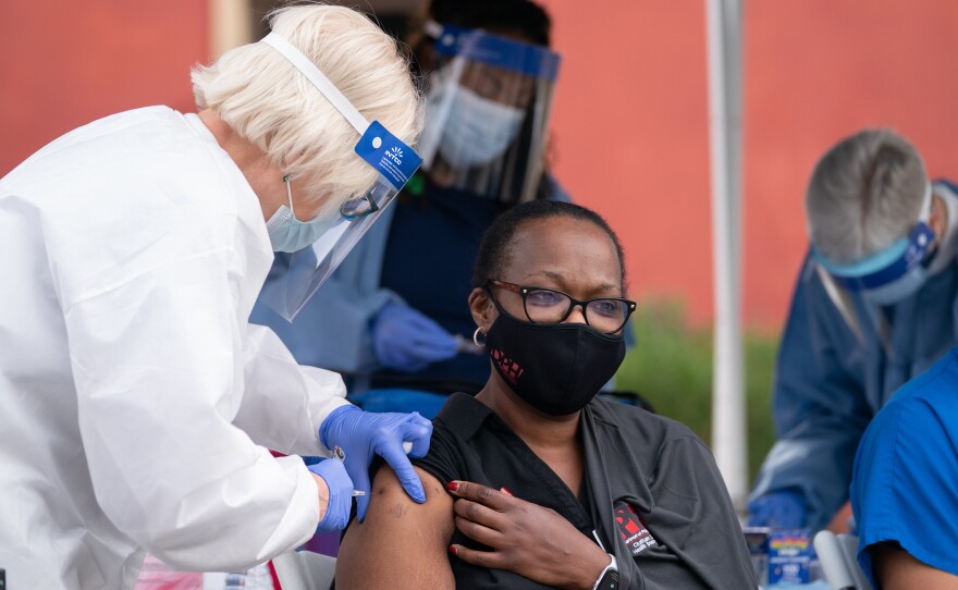 Tammi Brown (right), the Chatham County Health Department nurse manager, receives a dose of the Pfizer-BioNTech COVID-19 vaccine from registered nurse Nancy Toth outside the Chatham County Health Department in Savannah, Ga., on Dec. 15.