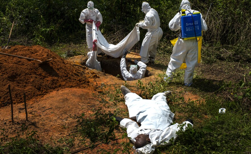 Alexander Morris lays flat on his back after he fainted due to the extreme heat inside a protective suit, while the Lofa County Health Department team buries his sister, on November 7, 2014 in Voinjama, Liberia.