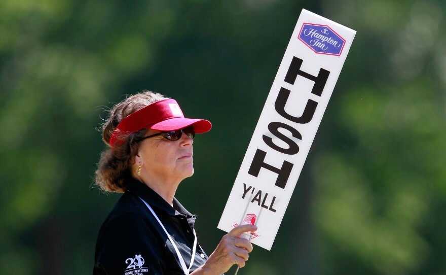 A volunteer holds up a "Hush Y'all" sign at an LPGA golf tournament in 2012 in Mobile, Ala.