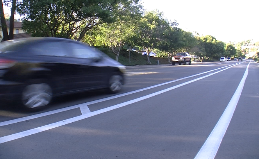 A car drives past a buffered bike lane on Collwood Boulevard in the College Area, Feb. 12, 2016.