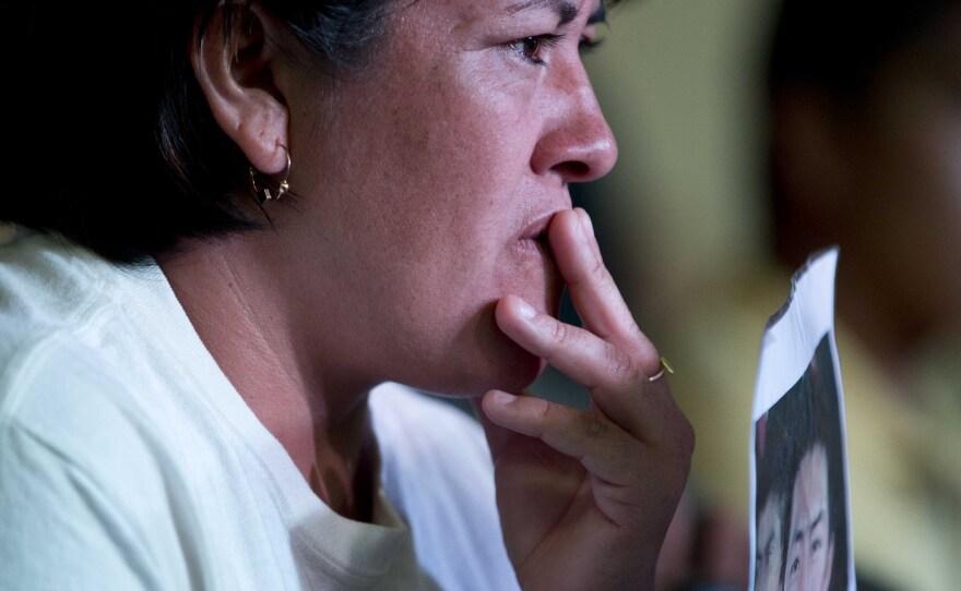 A relative holding a picture of one of the missing students listens in during a press conference by the family members of the missing, in Mexico, City, Jan. 27, 2015.