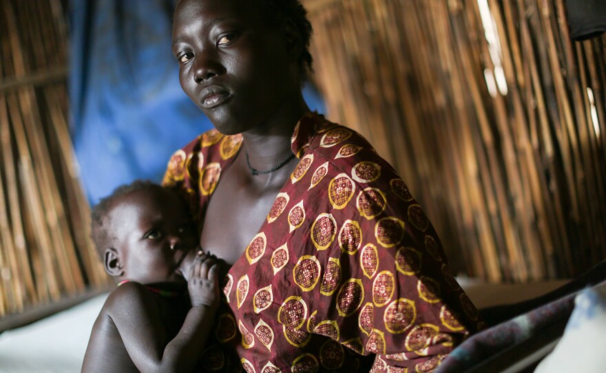 "I saw people killed in front of me," says 26-year-old Tavitha Nyaluak, explaining why she came to this camp. She's nursing her 2-year-old daughter in their shelter.