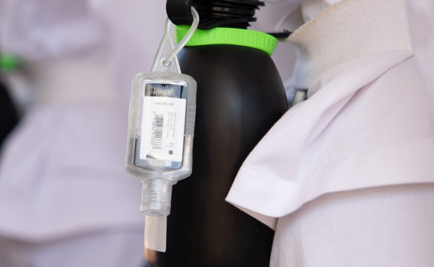 A bottle of hand sanitizer is attached to a water canteen on a freshman's belt.