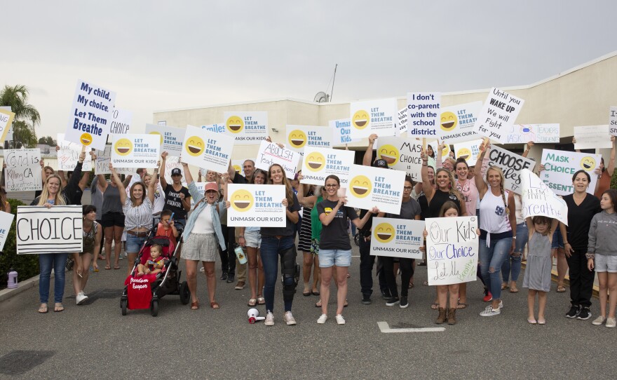 Undated photo of a group of people holding "Let Them Breathe" signs in protest of masks in schools. Sharon McKeeman, the founder of the organization stands in the middle next to a blowhorn.