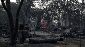 A flag flies in the charred rubble of a home burned in the Carr Fire, Saturday, Aug. 11, 2018, in Redding, Calif.