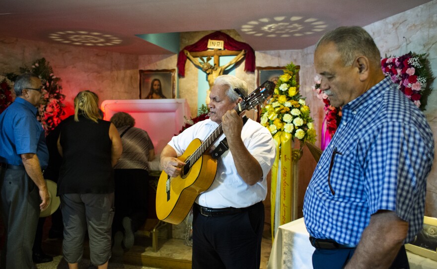 Gary Nuñez (center) sings as family and friends pay their respects at Irizarry's wake.