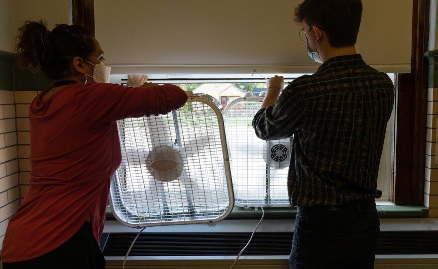Quesada and student teacher Christopher Wolfzorn place box fans in open windows to keep air circulating. After doing her own research, Quesada decided to face one fan outward and one fan inward for better circulation.