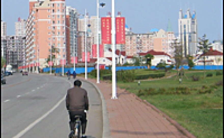 A Chinese bicyclist pedals past new housing going up along the riverfront in the border city of Dandong, China.