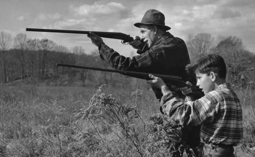 A man and a boy out hunting with shotguns, circa 1955.