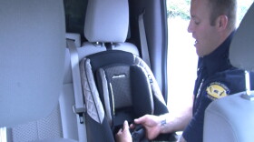 Travis Hoberecht, of American Medical Response, demonstrates the proper way to install a child restraint, July, 7, 2015.