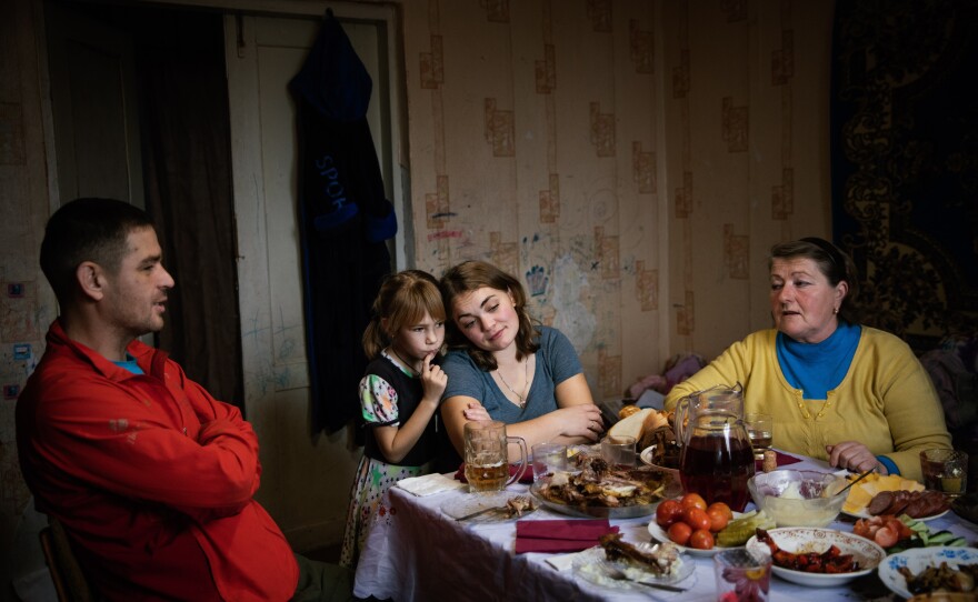 Left to right: Dmytro Drobysh, his wife Hanna, their daughter Angelina and neighbor Olena Dovhozhenko eat lunch in Poltava region. The Drobysh family are part of the Grinik's extended family and the reason they came here when Russia invaded. December 2022.