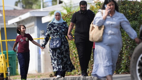 People hold hands near the scene of a shooting outside the Islamic Center of San Diego on Monday.